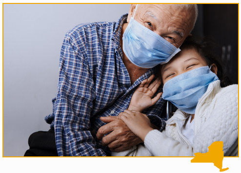 People embracing and smiling while wearing surgical masks