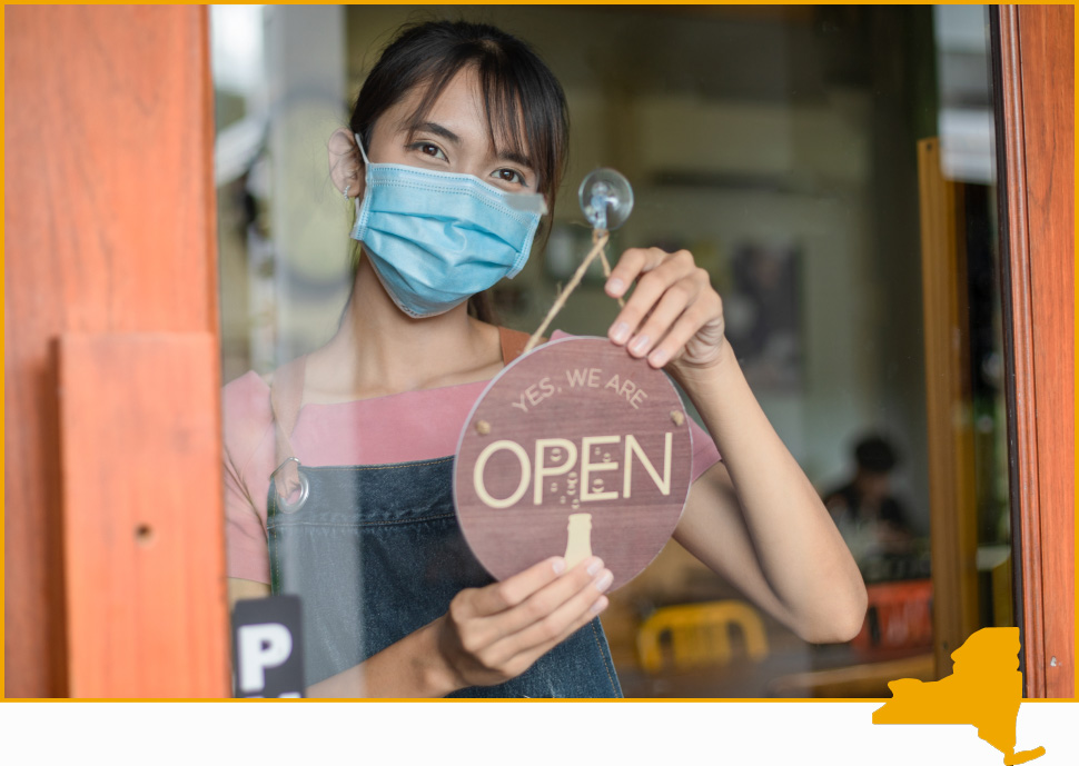 Woman in mask holding 'Open' sign