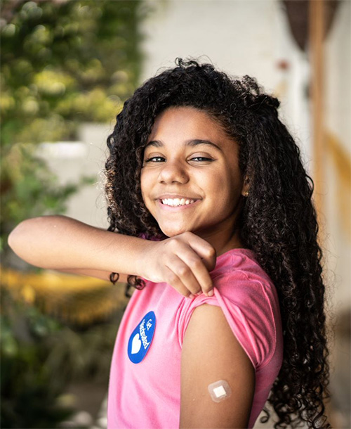 Child raising sleeve to show post-vaccination bandage